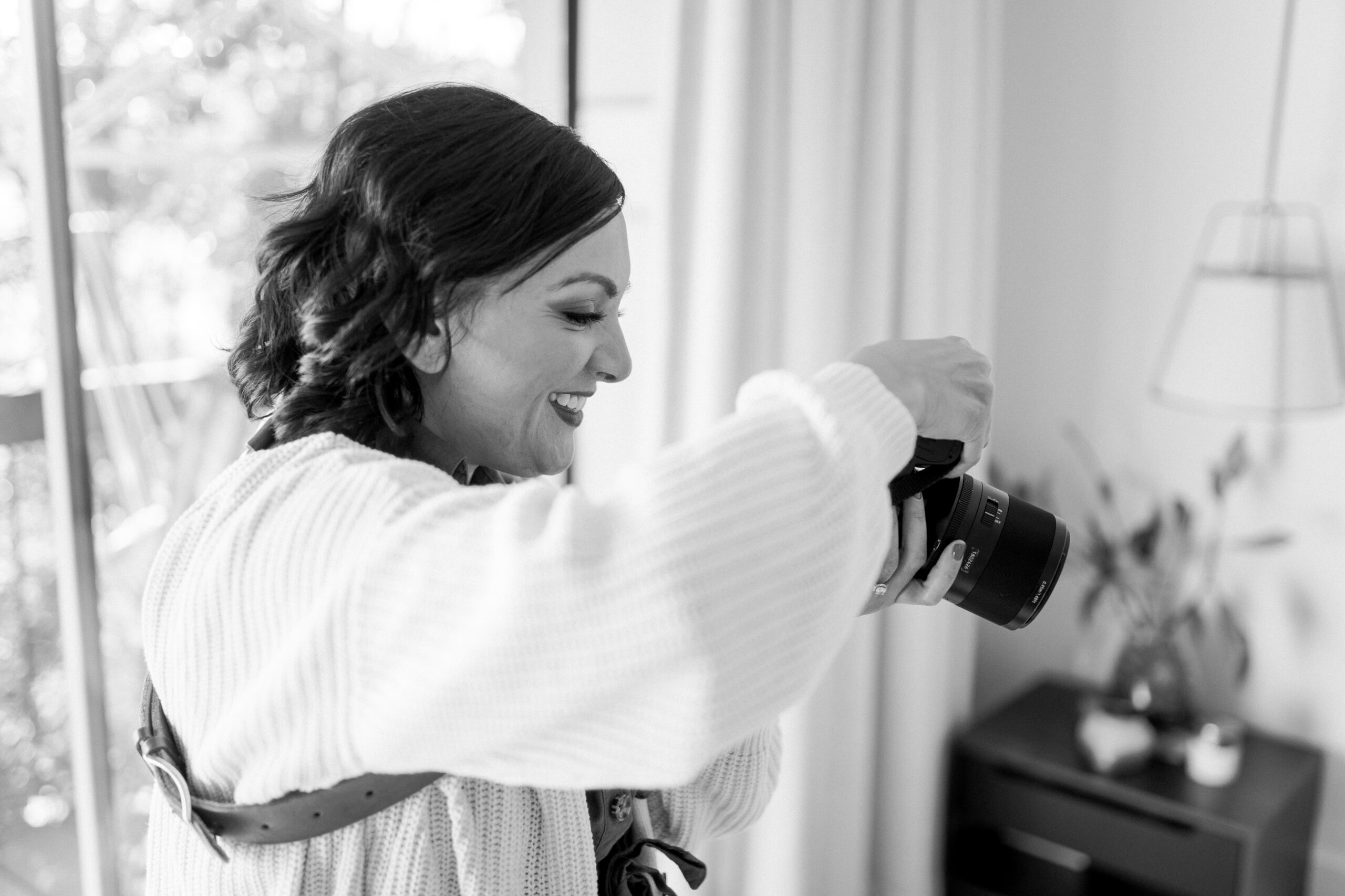 a black and white image of a female photographer holding a camera and taking a photo